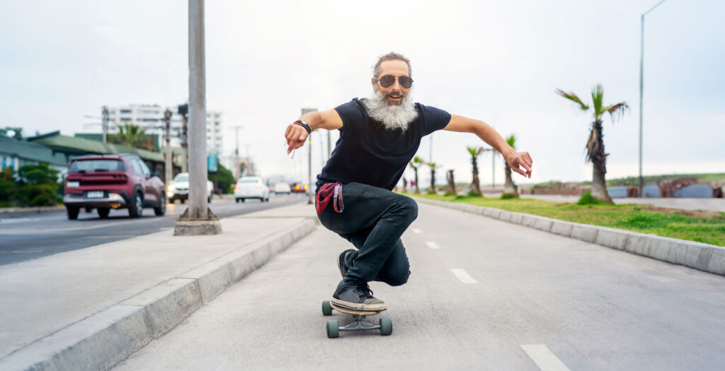 Content that's not for traditional demographic. Latin senior man skateboard on bikeway and having fun.