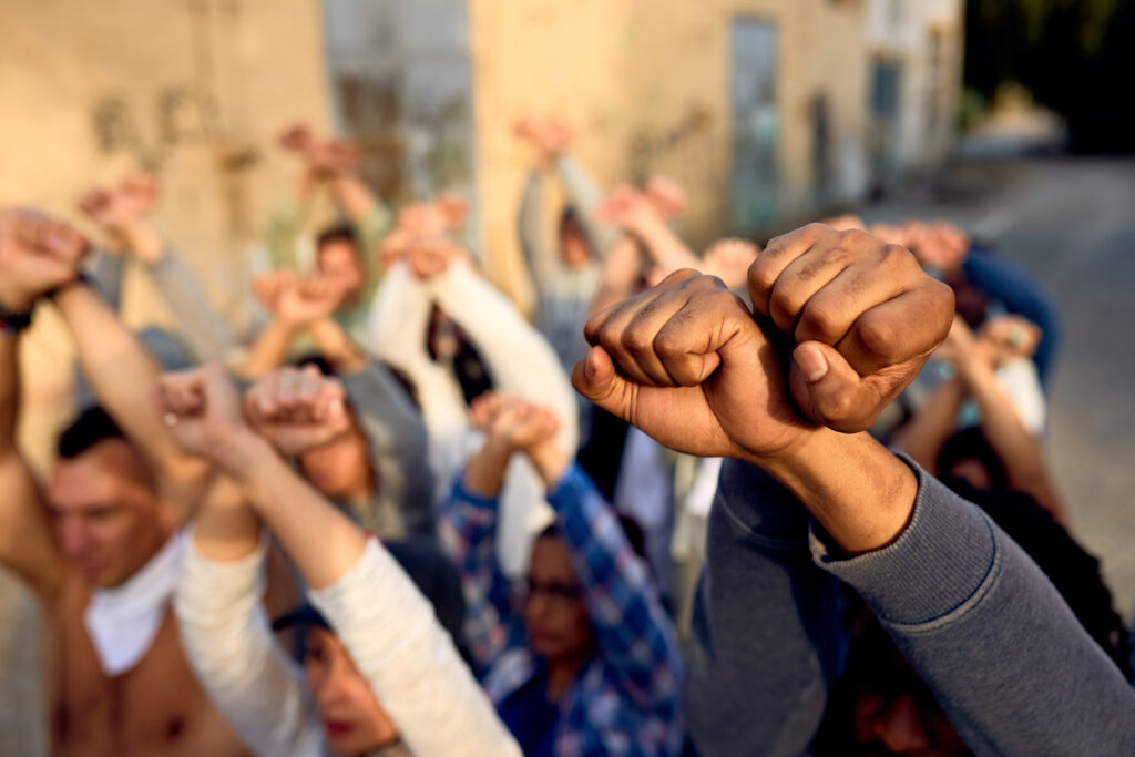 Crowd of people at a protest with fists in the air. DEI representation.